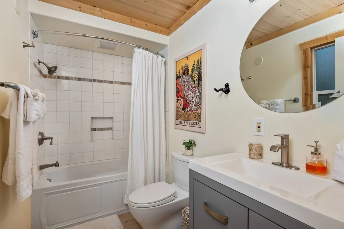 A peaceful bathroom scene with an inviting bathtub, simple artwork, and a sleek sink. Soft lighting and uncluttered design encourage restful self-care, mirroring spa experiences.