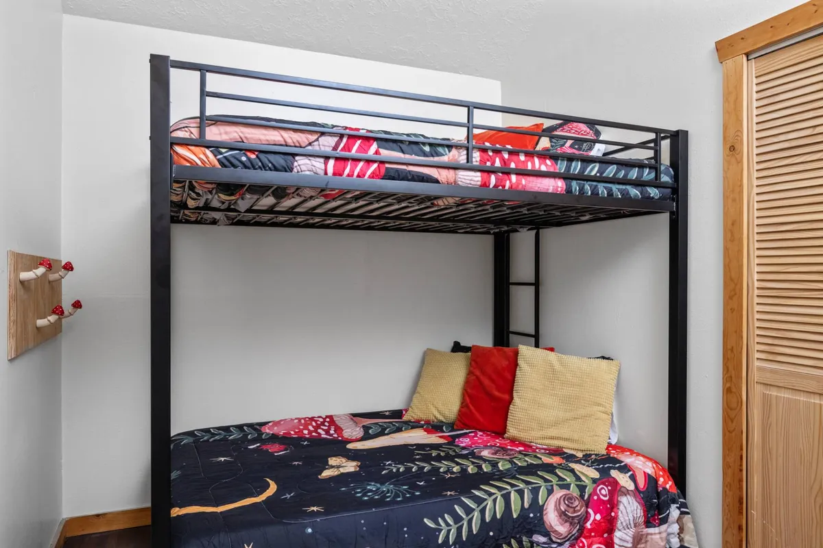 A playful bedroom featuring a bunk bed with colorful bedding and decorative pillows, radiating warmth and fun. The vibrant atmosphere caters to children and young-at-heart guests, inviting imaginative play and cozy sleepovers.